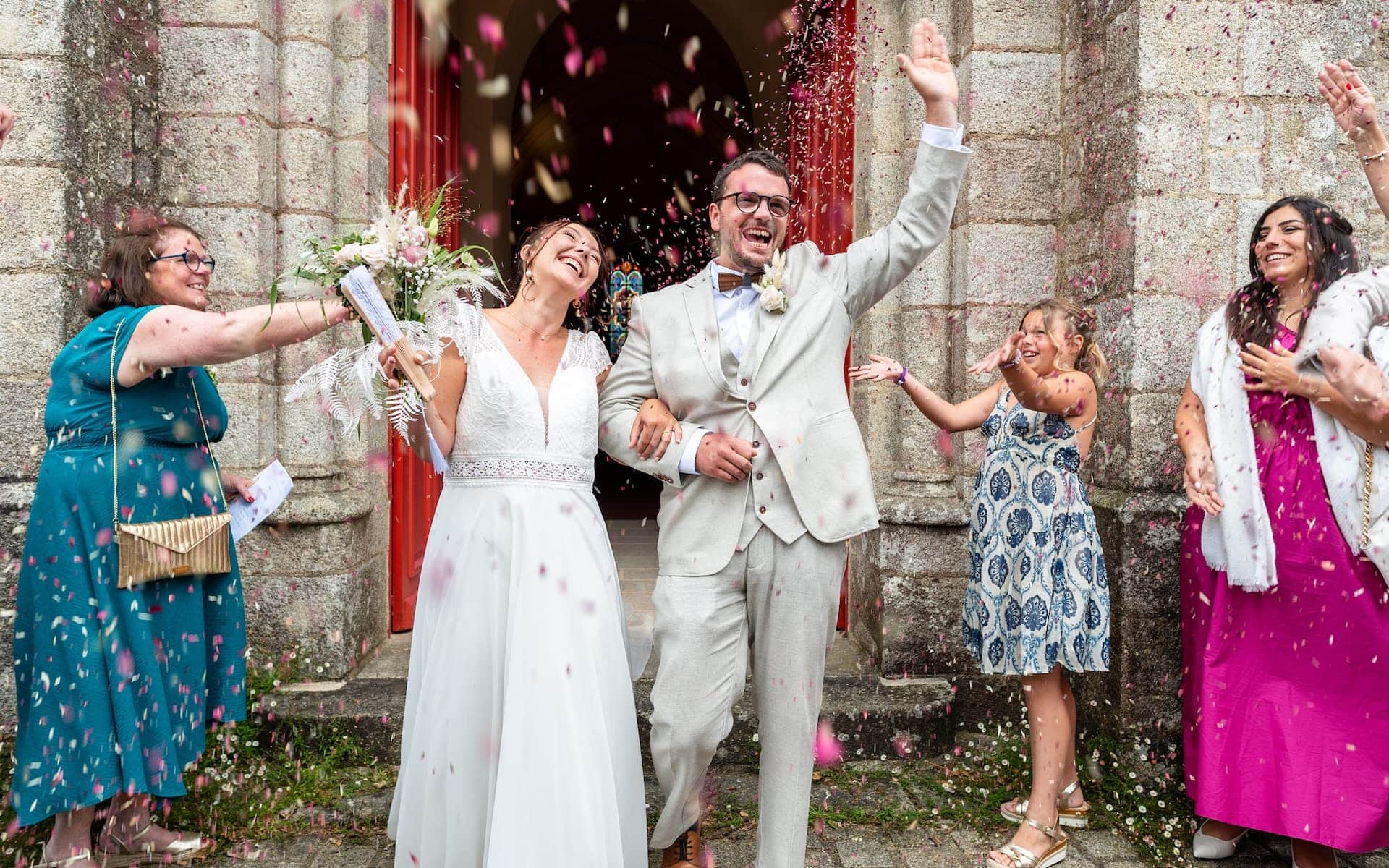 Mariés sortant de l'église sous les confettis, moment spontané en reportage mariage